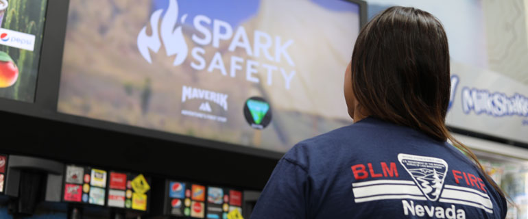 BLM Firefighter Looks at Spark Safety Ad in Maverik Store