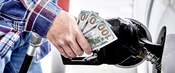 Man feeding cash into a gas tank